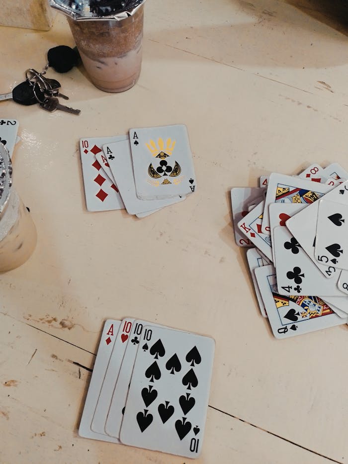 A casual card game setup with drinks on a wooden table, featuring playing cards.